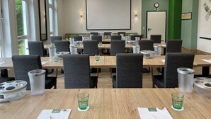 A conference room with tables, chairs, and a projector screen.