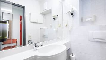 A modern bathroom with a large sink, a mirror, and a shower area.