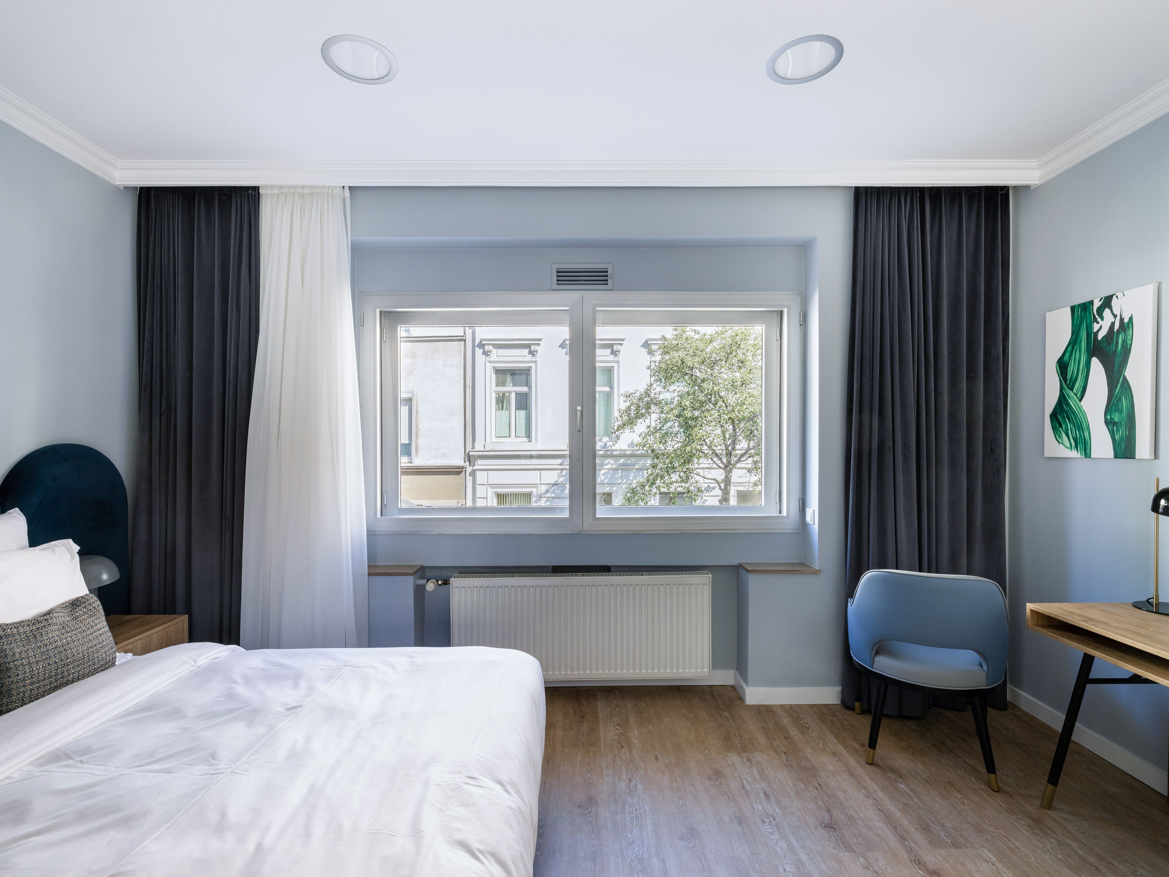 A modern hotel room with a large bed, a desk, and a chair.