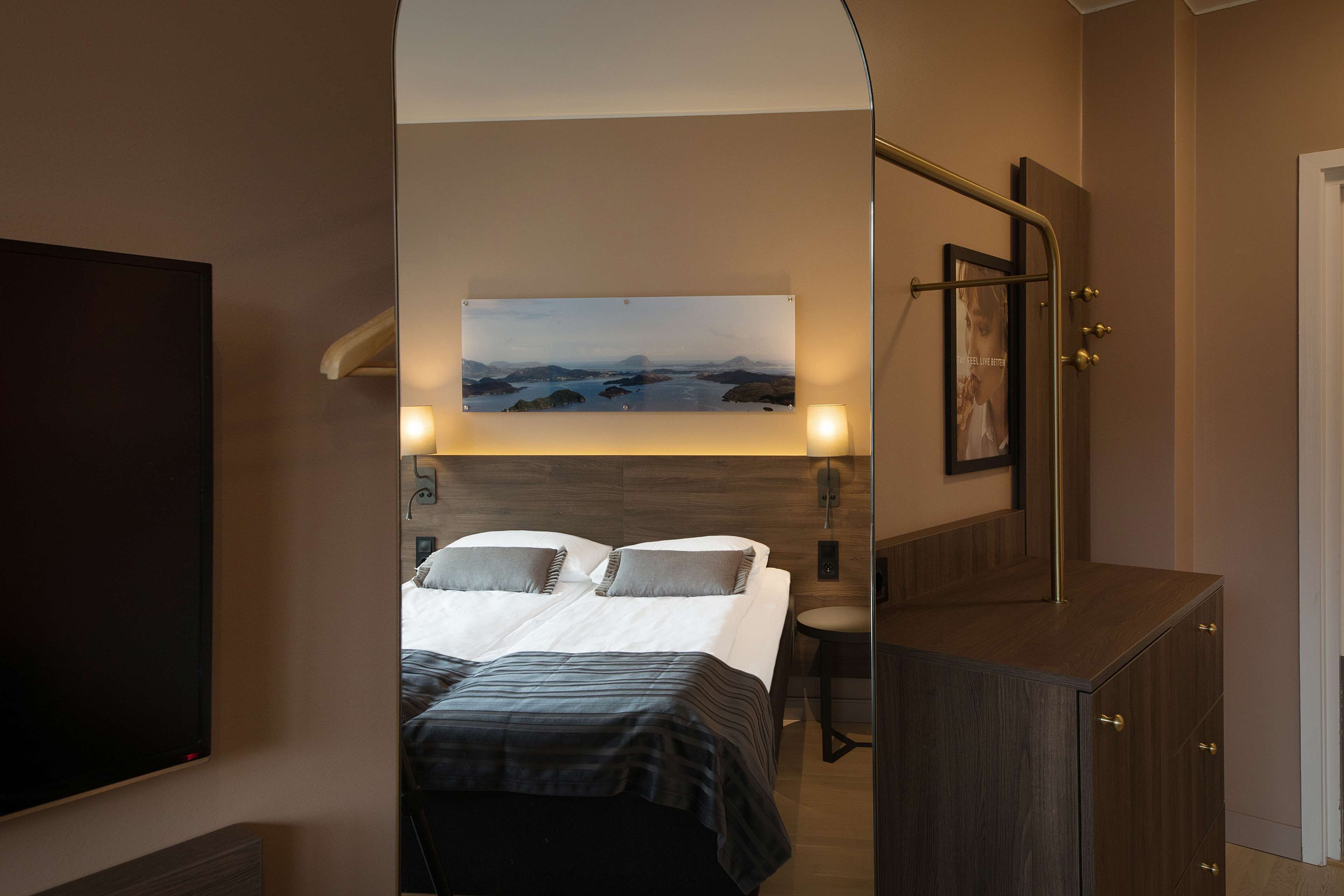 Una camera d'albergo con un letto, una televisione, un quadro e uno specchio.