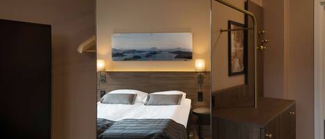 A hotel room with a bed, a TV, a painting, and a mirror.