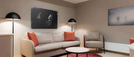 Una sala de estar moderna con un sofá, sillones, una mesa de centro y dos lámparas de pie.