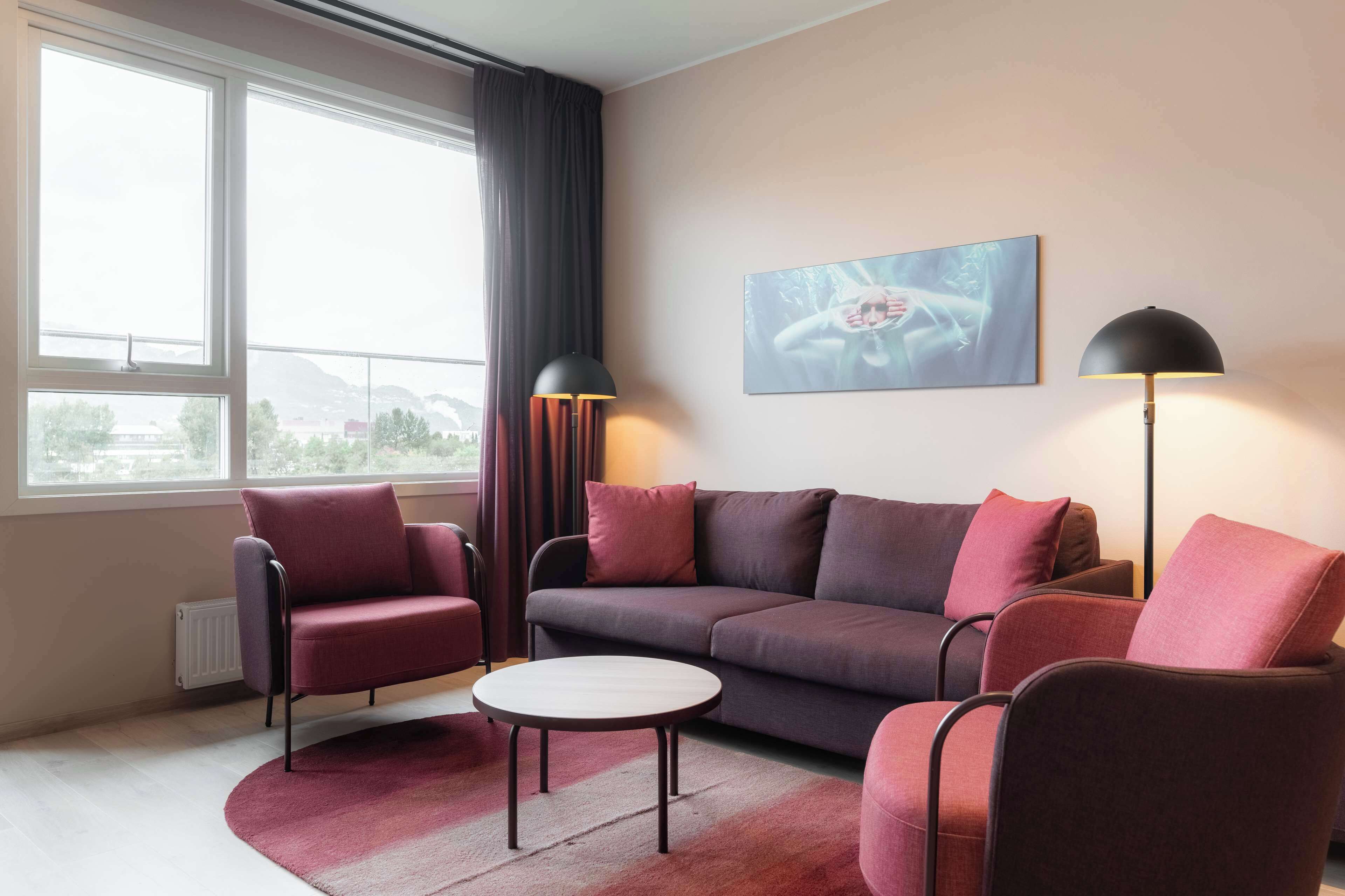 A modern living room with a sofa, armchairs, a coffee table, and two floor lamps.