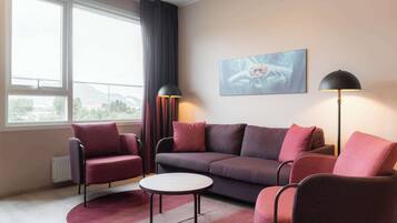 A modern living room with a sofa, armchairs, a coffee table, and two floor lamps.
