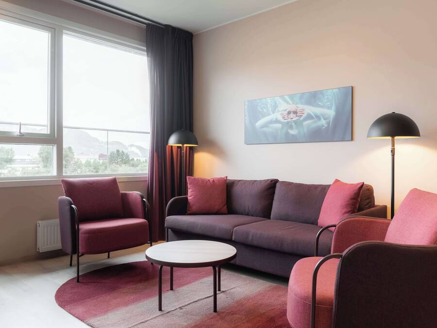 A modern living room with a sofa, armchairs, a coffee table, and two floor lamps.
