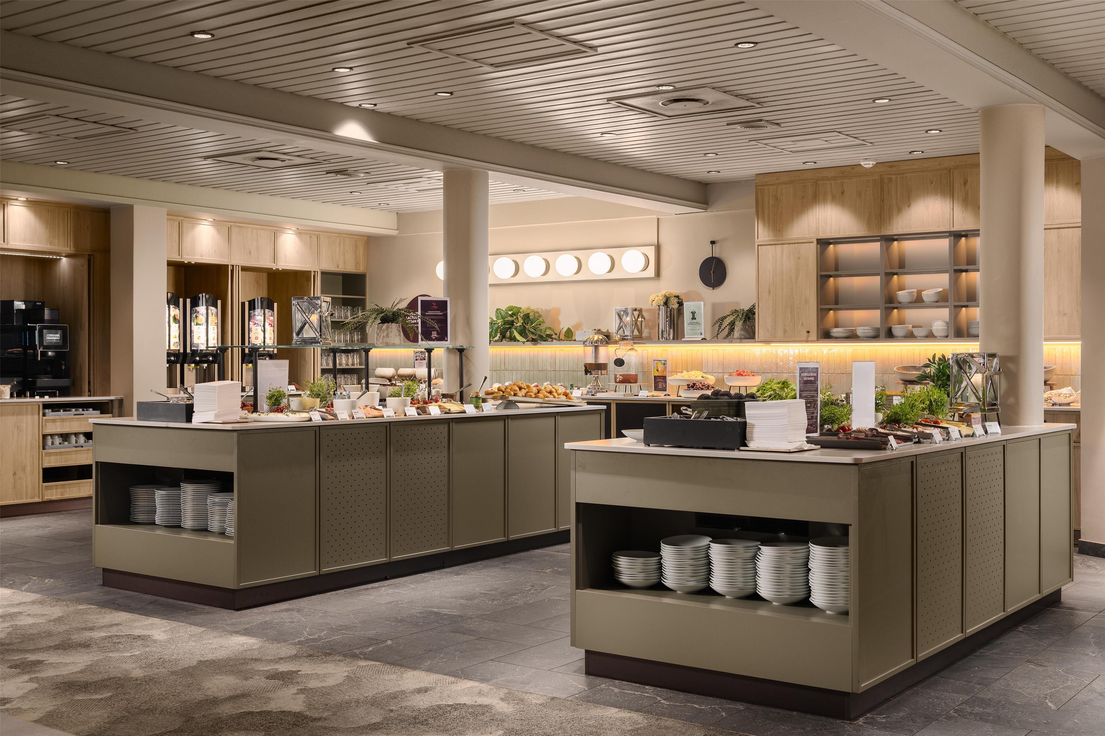 A modern hotel lobby with a reception desk, seating area, and a buffet counter.