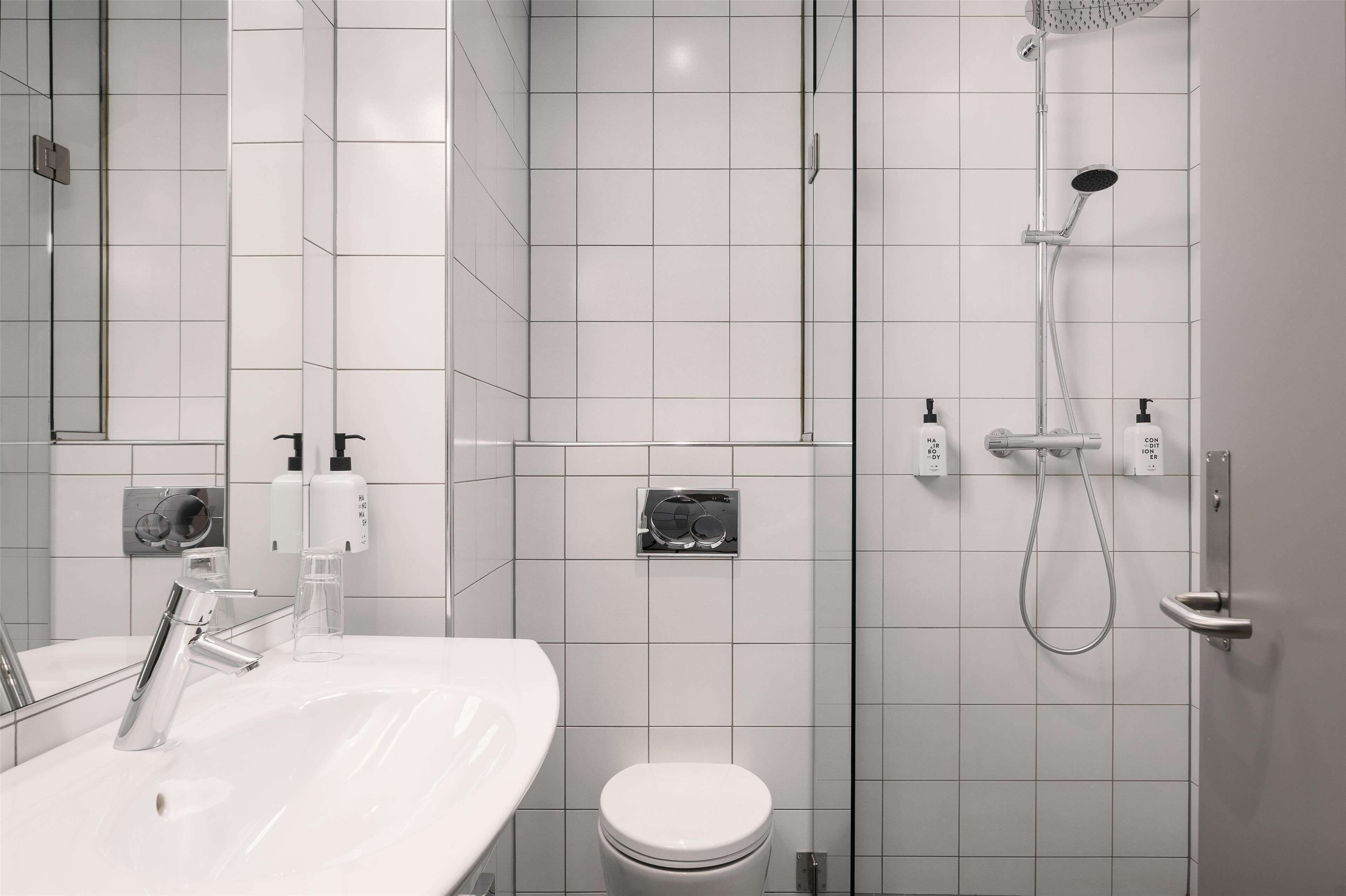 A modern bathroom with a white sink, toilet, and shower area.