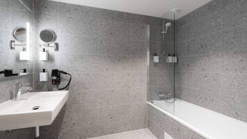 A modern bathroom with a white sink, a round mirror, and a glass-enclosed shower area.