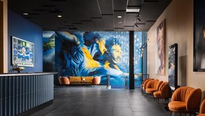 A modern lobby with a reception desk, seating area, and a large mural on the wall.