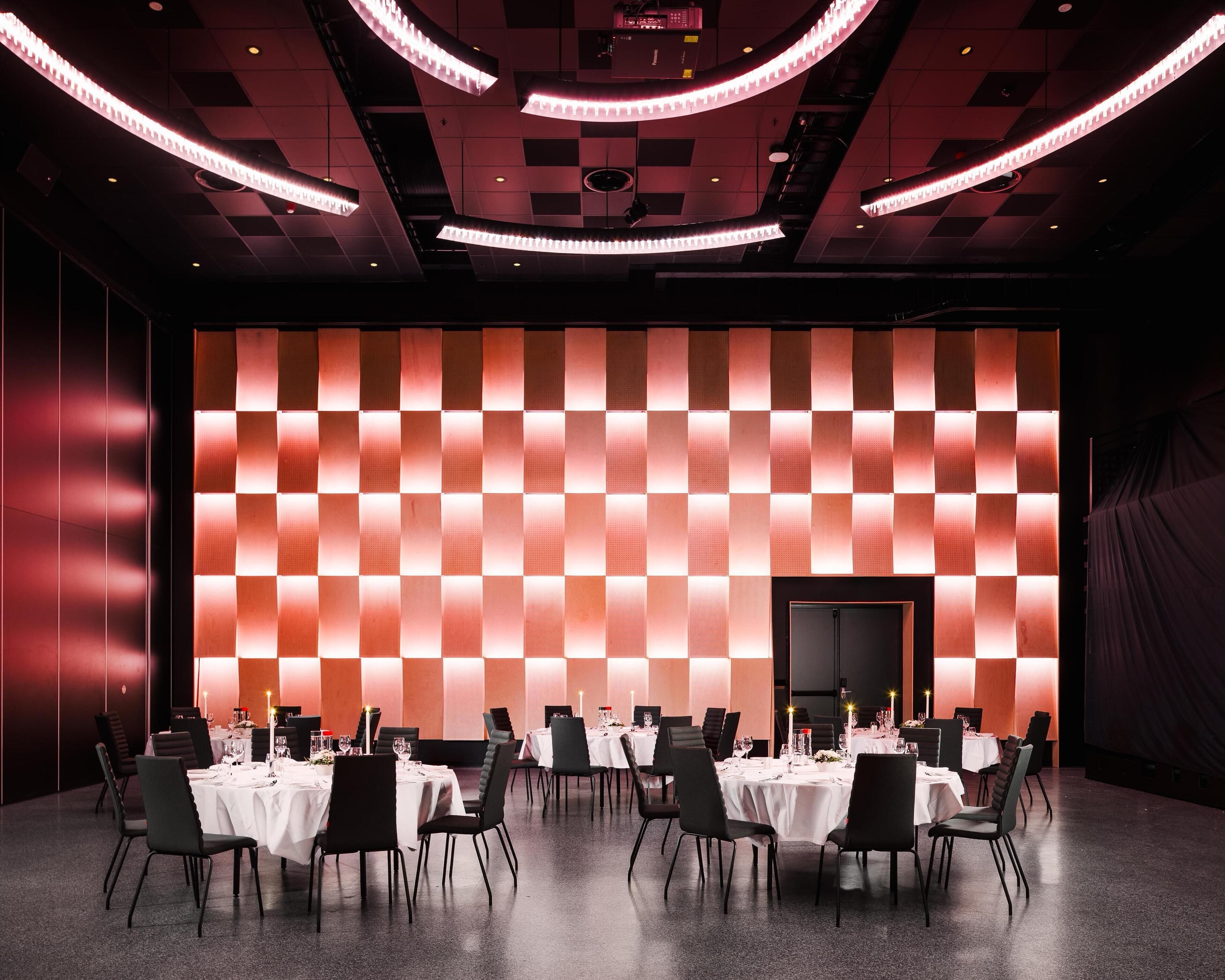 A conference room with a checkered wall pattern, white tables, and black chairs.