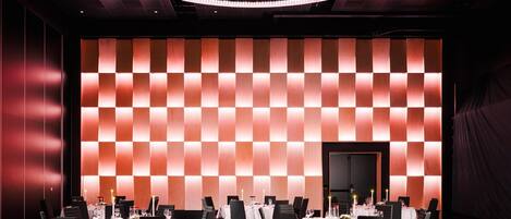 A conference room with a checkered wall pattern, white tables, and black chairs.