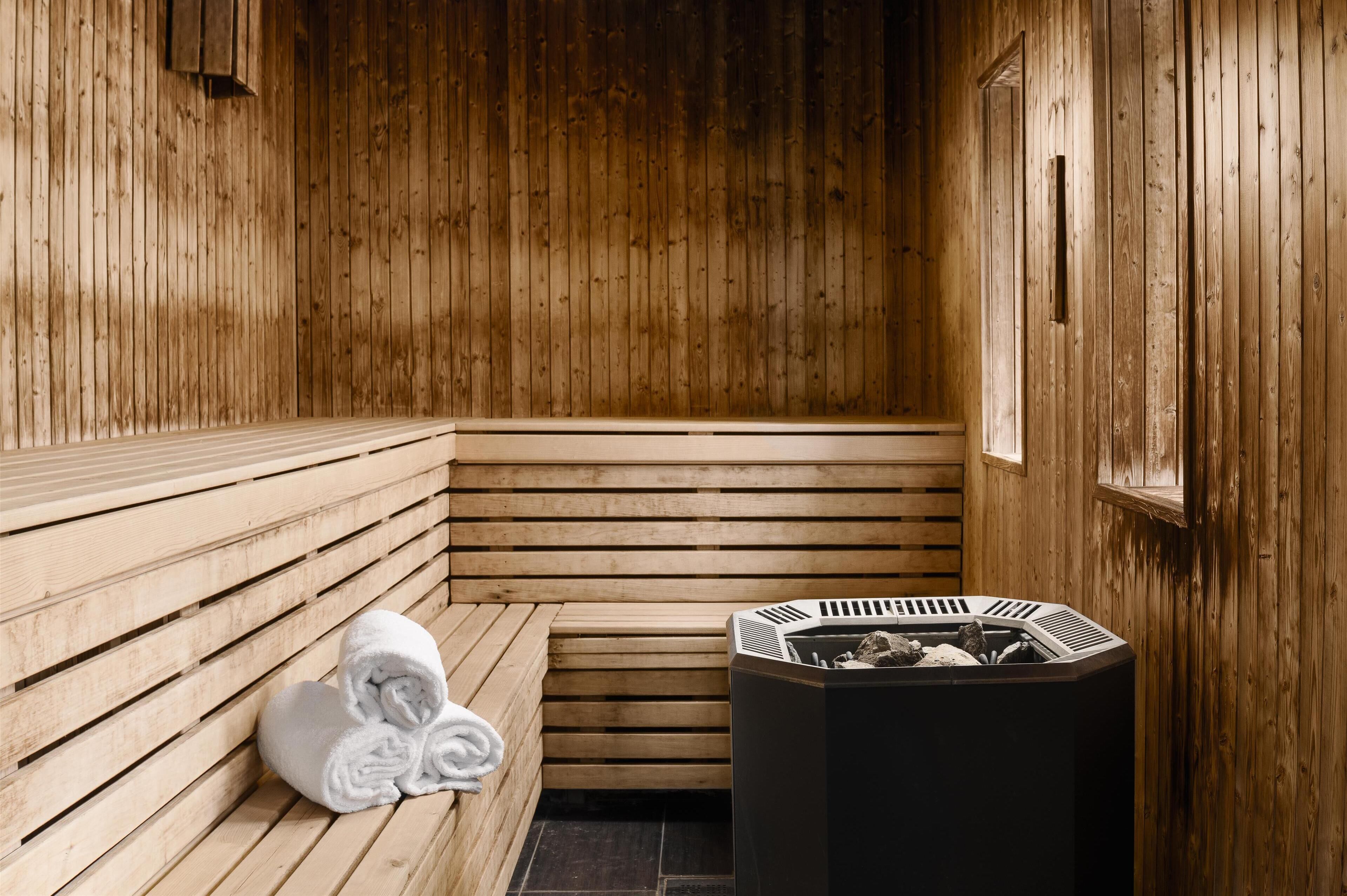 Una sauna de madera con bancos y una estufa central.