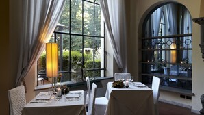 A dining area with two tables, white tablecloths, and a large window with curtains. - Hotel Villa Stanley (Sesto Fiorentino)