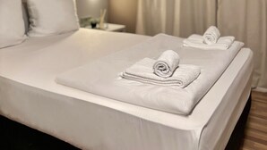 A hotel room with a neatly made bed, a bedside lamp, and a window with curtains. - Colour Hotel (Frankfurt)