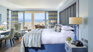 A hotel room with a large bed, a desk with a chair, a lamp, and a view of the sea. - The Eliott Hotel (Gibraltar)