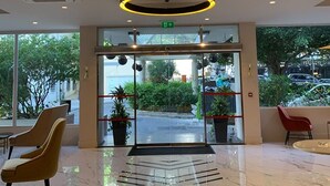 A modern hotel lobby with a marble floor, a reception desk, and a glass door entrance. - The Eliott Hotel (Gibraltar)