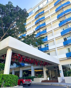 A multi-story hotel with balconies, a covered entrance, and a red vintage car parked in front. - The Eliott Hotel (Gibraltar)