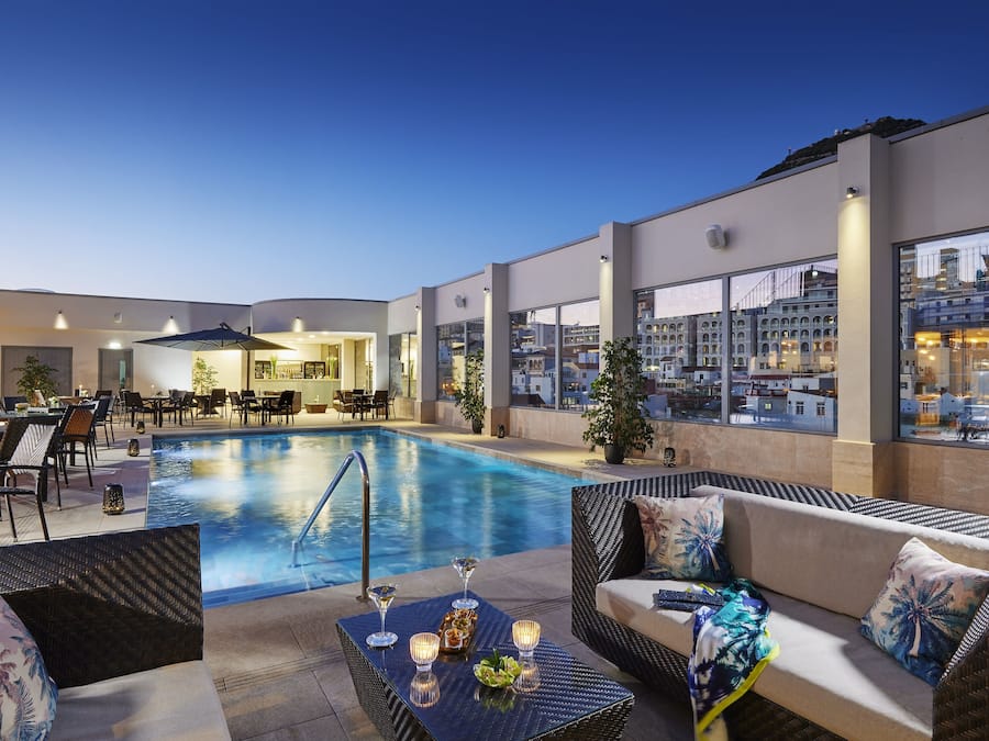 Una piscina al aire libre, sombrillas, sillones reclinables de piscina