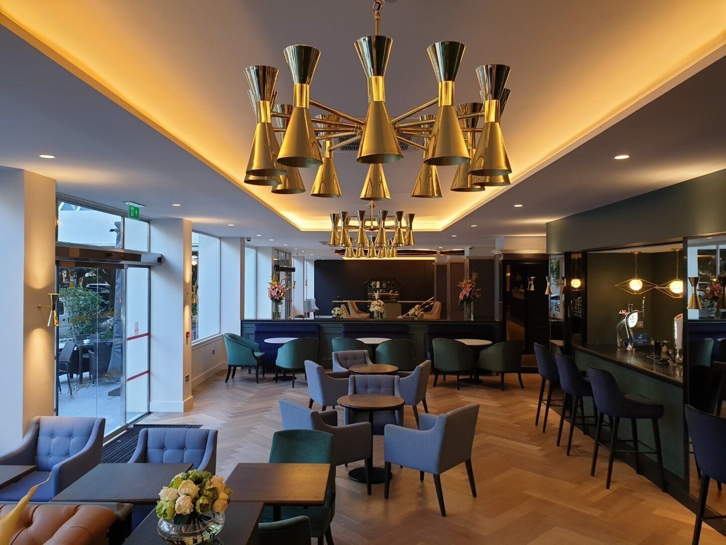A modern hotel lobby with a bar area, seating arrangements, and a chandelier.