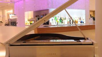 Un pianoforte a coda in una stanza ben illuminata, con un bar sullo sfondo.