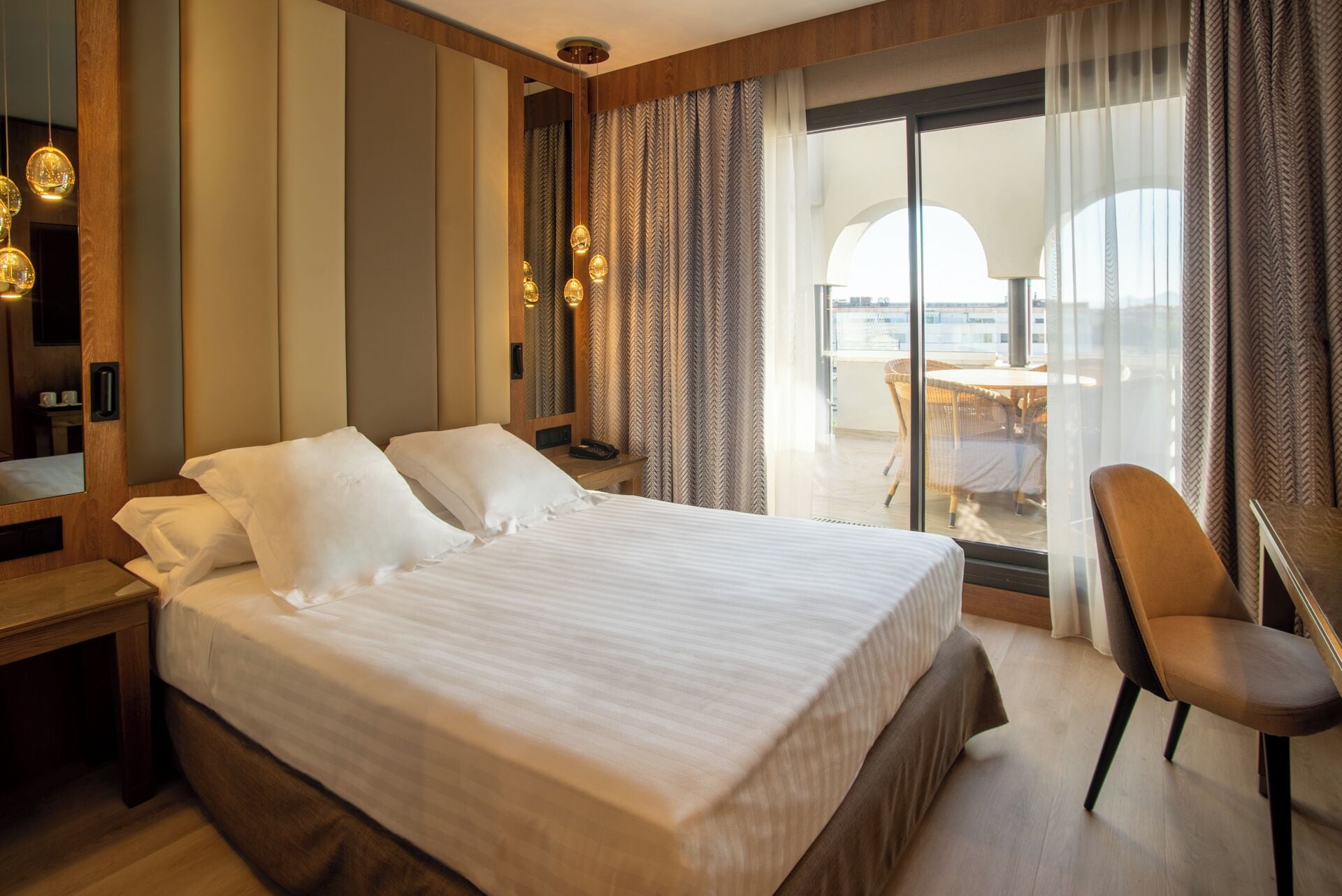 A hotel room with a large bed, a chair, a desk, and a view of the outdoors.