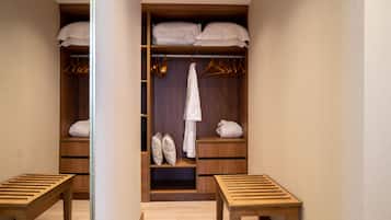Un vestidor con estantes de madera, una barra para colgar ropa y un banco.