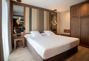 Un dormitorio moderno con una cama grande, un armario de madera y una mesita de noche con lámpara.
