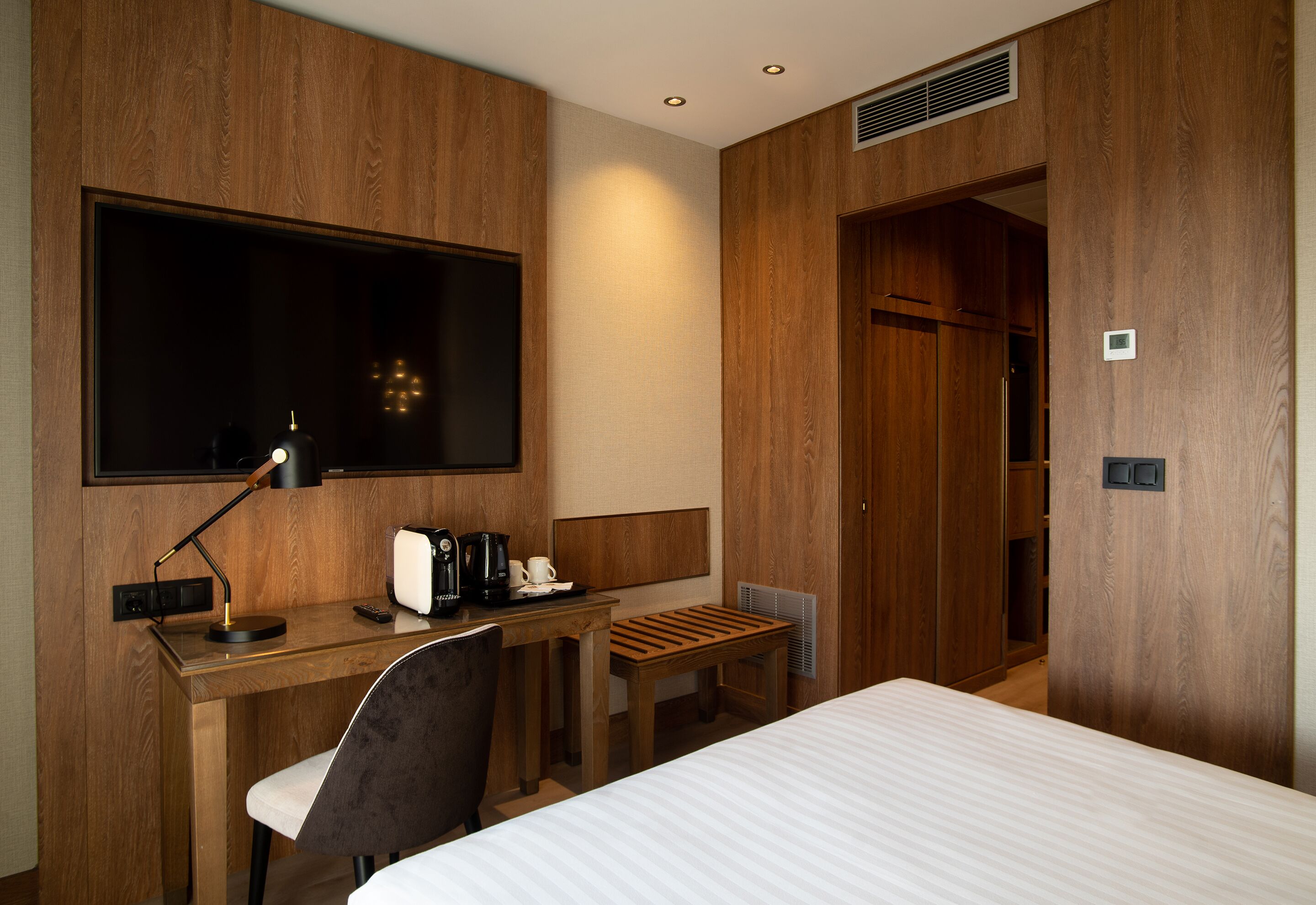 A hotel room with a bed, desk, chair, and a television.