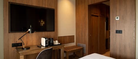 Una habitación de hotel con cama, escritorio, silla y televisión.