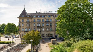 A large brick building with the sign "GRAND HOTEL" on the roof, surrounded by greenery and parked bicycles. - Grand Halmstad, WorldHotels Crafted (Halmstad)