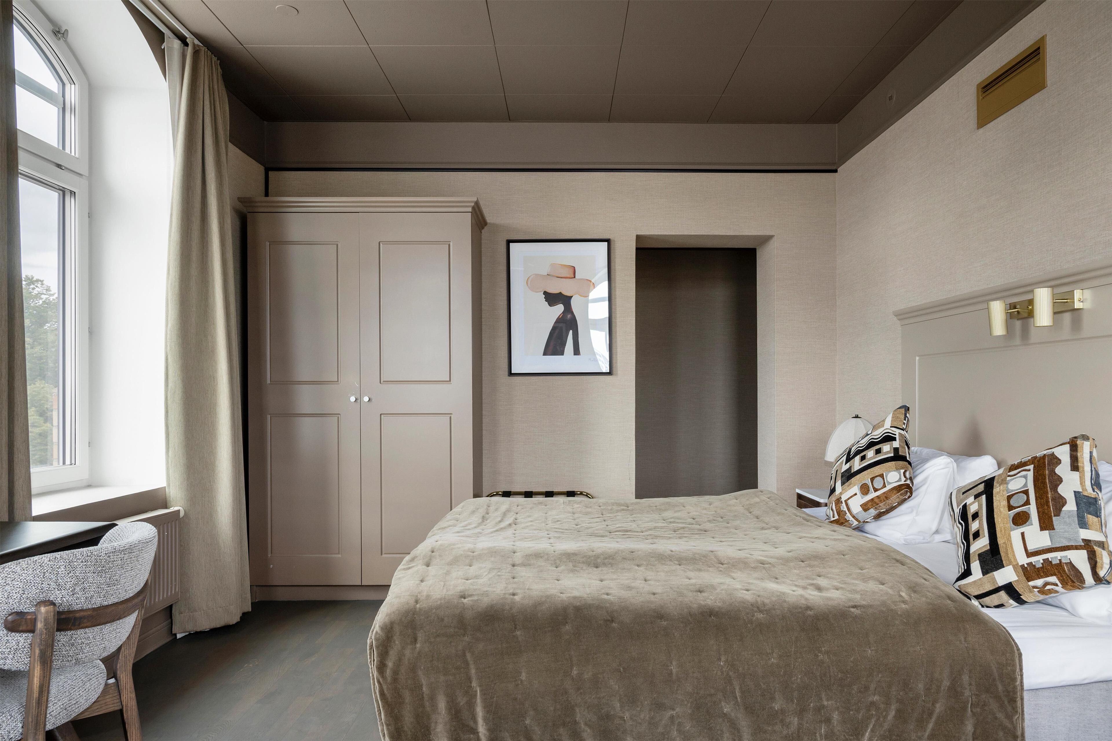 A bedroom with a bed, a desk, and a wardrobe.