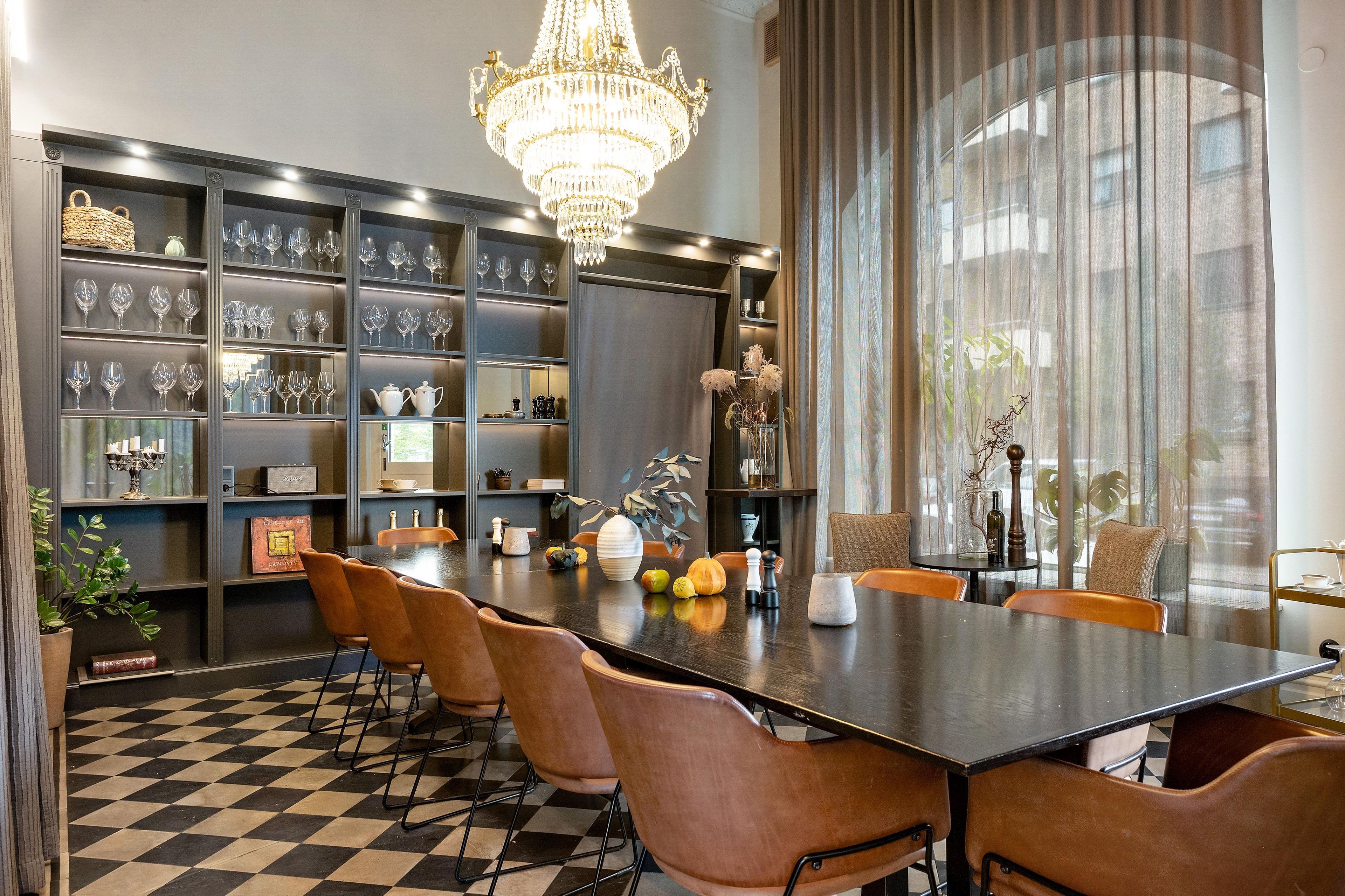 A dining area with a checkered floor, a chandelier, and a table with chairs.