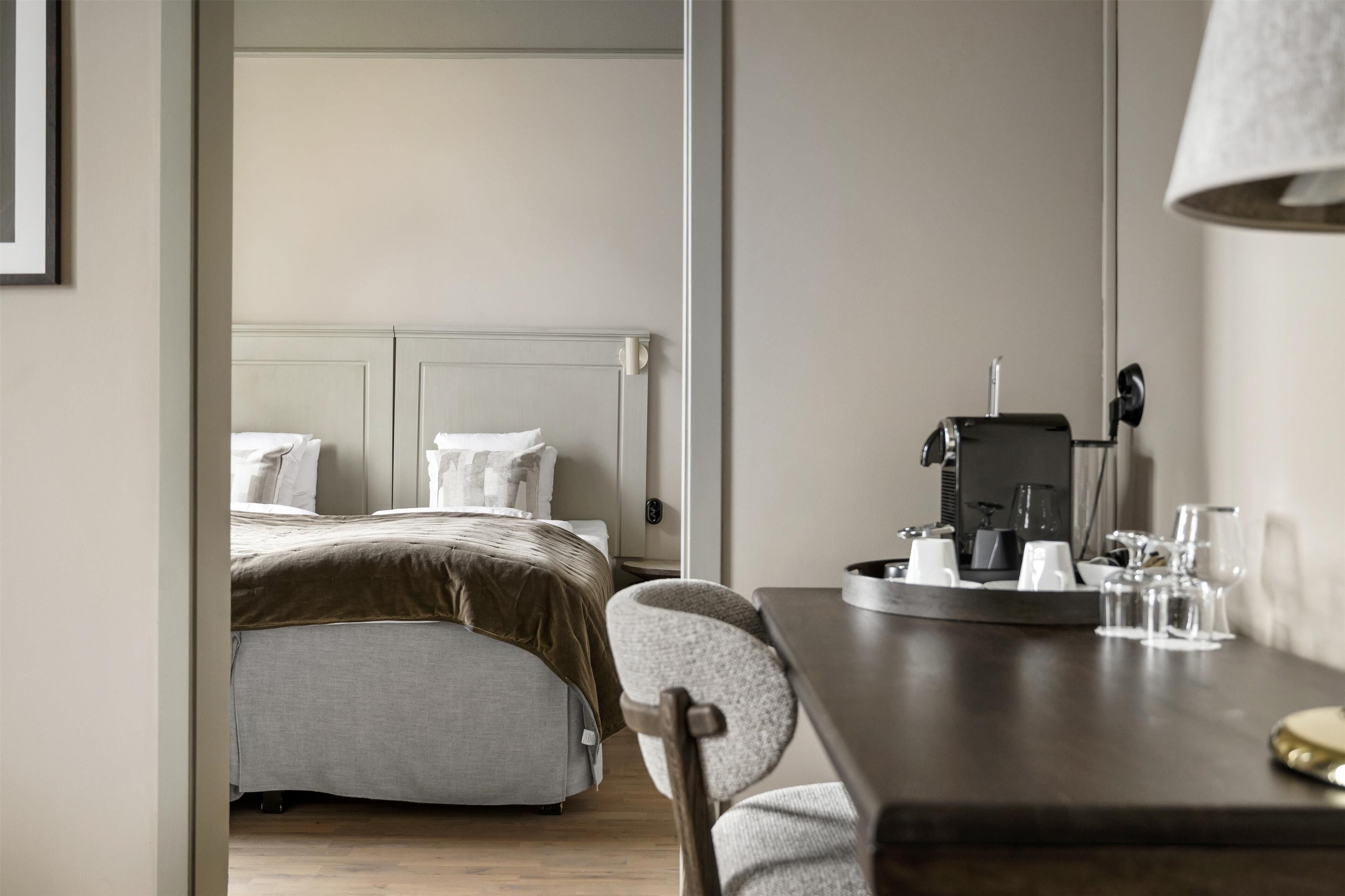Ein Hotelzimmer mit Bett, Schreibtisch mit Lampe und einer Kaffeemaschine.