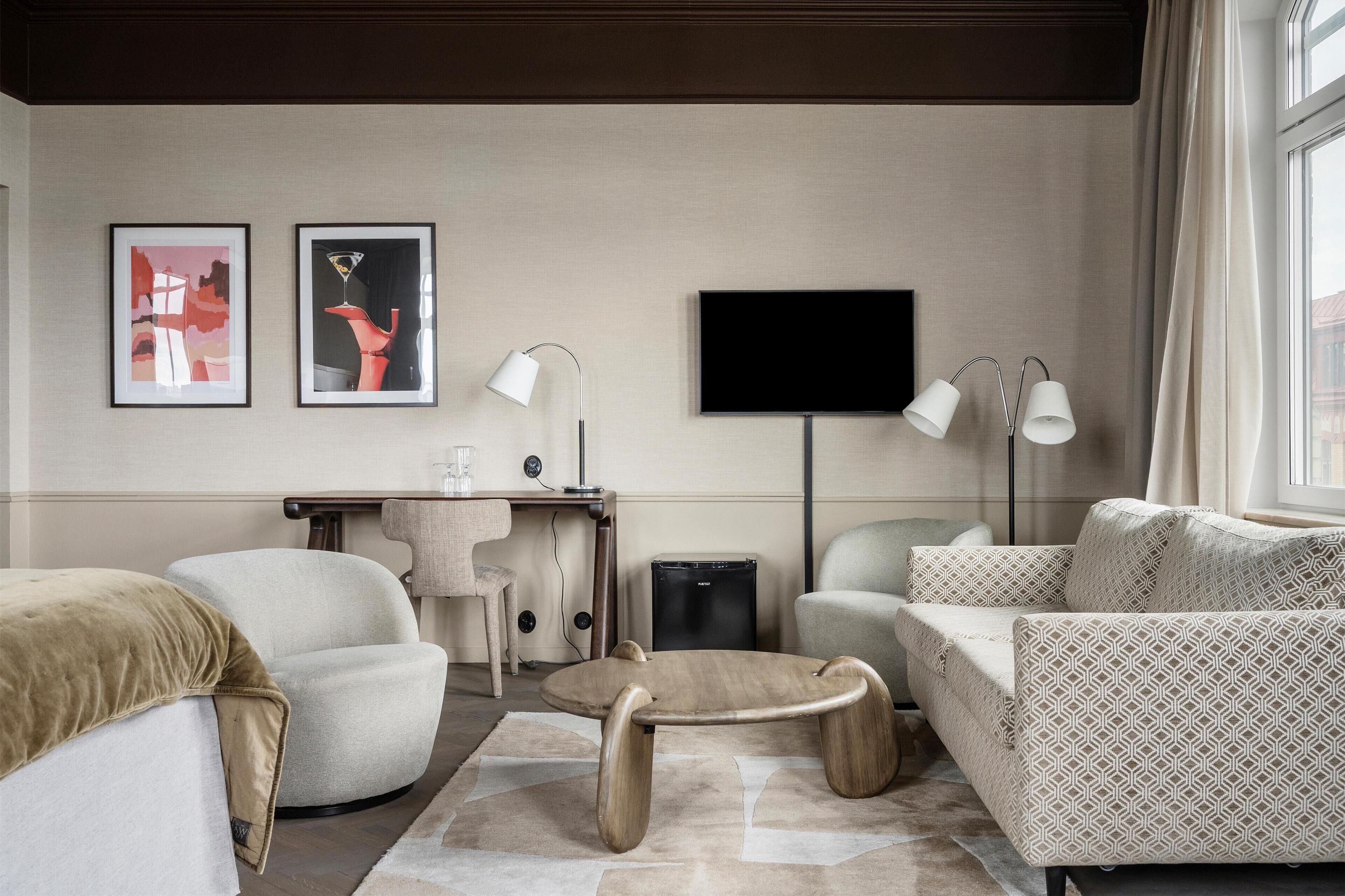 Ein modernes Wohnzimmer mit einer Couch, einem Sessel, einem Couchtisch und Kunstwerken an der Wand.