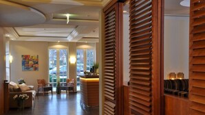 Um saguão de hotel com balcão de recepção, área de estar e grandes janelas.