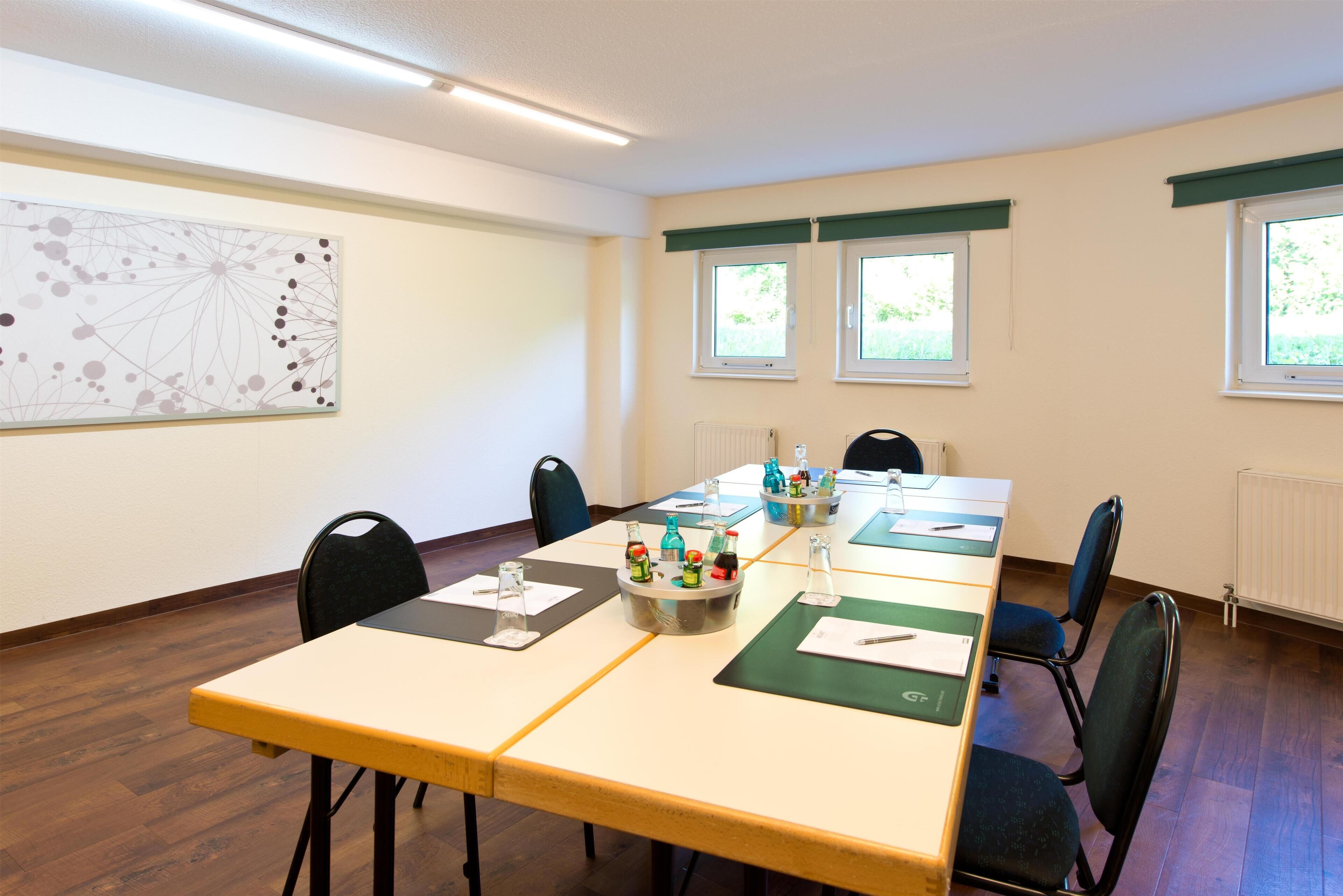 Ein Konferenzraum mit einem langen Tisch, Stühlen und einer Projektionsleinwand.