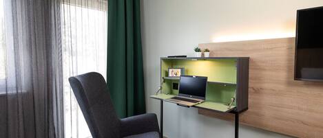 Ett rum med ett skrivbord, en stol och en tv som är monterad på väggen.
