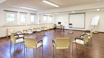 Ein Konferenzraum mit großem Bildschirm, mehreren Stühlen und einer Whiteboard-Tafel.