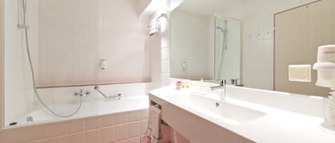 Un baño moderno con un espejo grande, una bañera y una ducha.