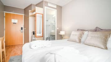 A hotel room with a large bed, a bathroom with a shower, and a door with a wheelchair symbol.