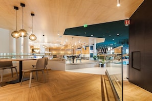Un interior moderno con suelo de madera, separaciones de vidrio y una escalera central.