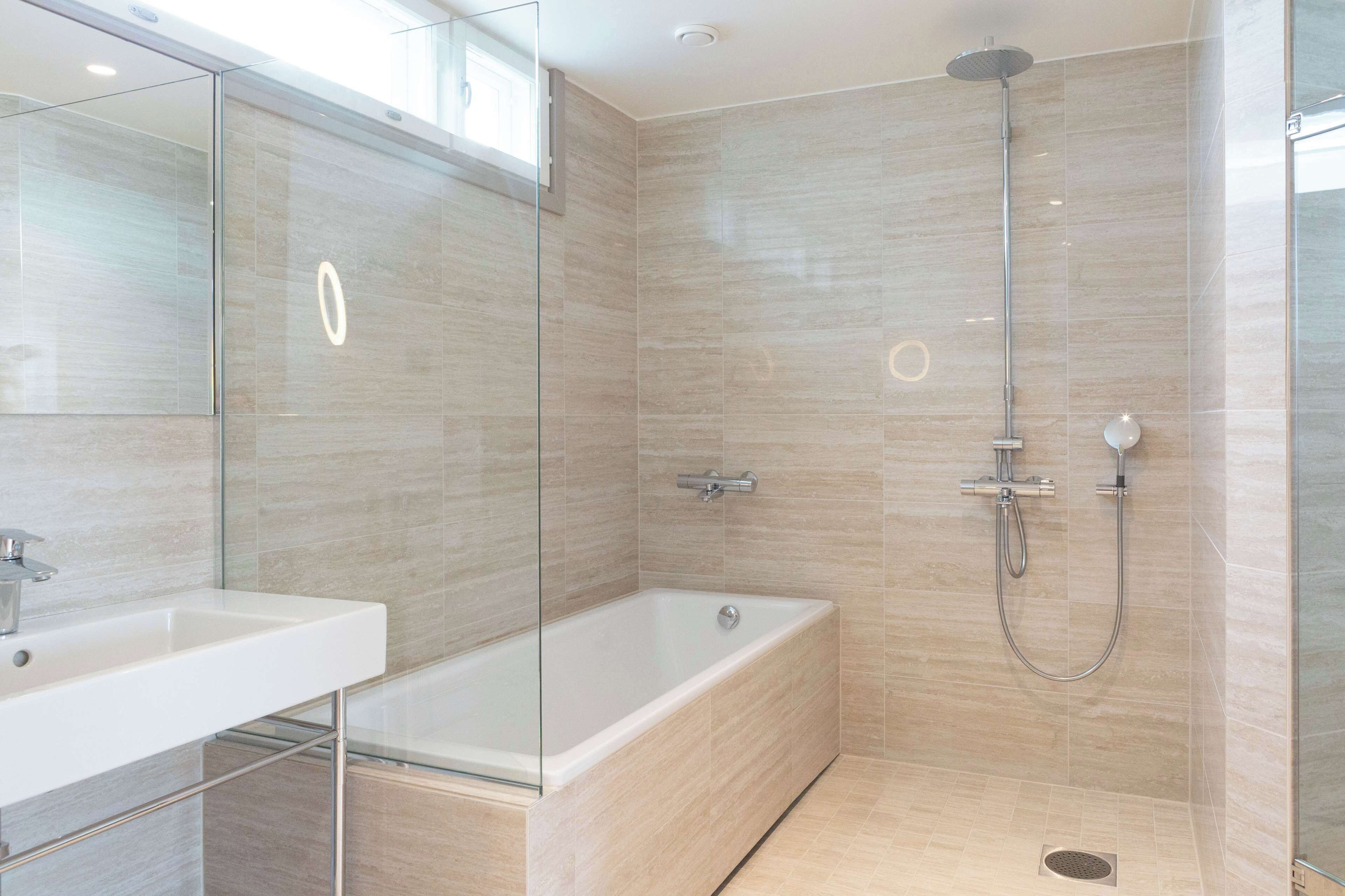 A modern bathroom with a glass-enclosed shower, a standalone bathtub, and a white sink.