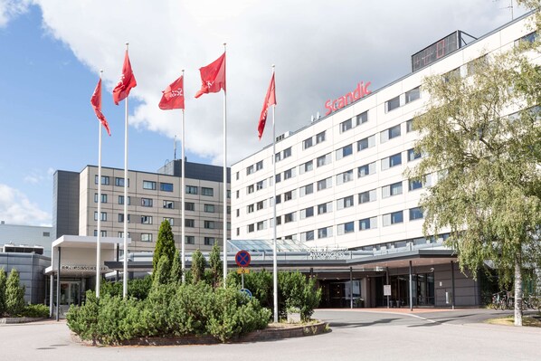 Un hotel moderno con varias banderas, un centro de convenciones y una entrada cubierta.