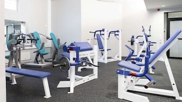 A gym with various exercise machines, a bench, and a door in the background.