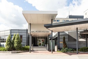 La entrada a un edificio con la leyenda "CONGRESS CENTER", un acceso cubierto, puertas de vidrio y un camino pavimentado.
