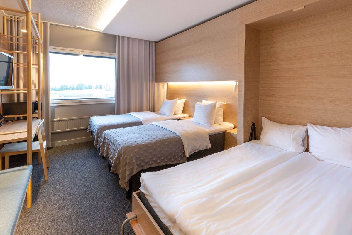 A hotel room with two beds, a desk, and a TV.