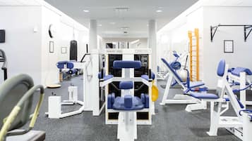 Un gimnasio con varios equipos de ejercicio, incluyendo máquinas de pesas y una cinta de correr.