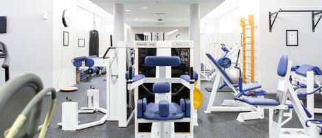 Un gimnasio con varios equipos de ejercicio, incluyendo máquinas de pesas y una cinta de correr.