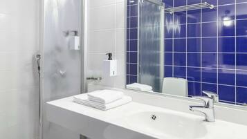 Une salle de bain moderne avec un lavabo blanc, un miroir et des murs recouverts de carreaux bleus.
