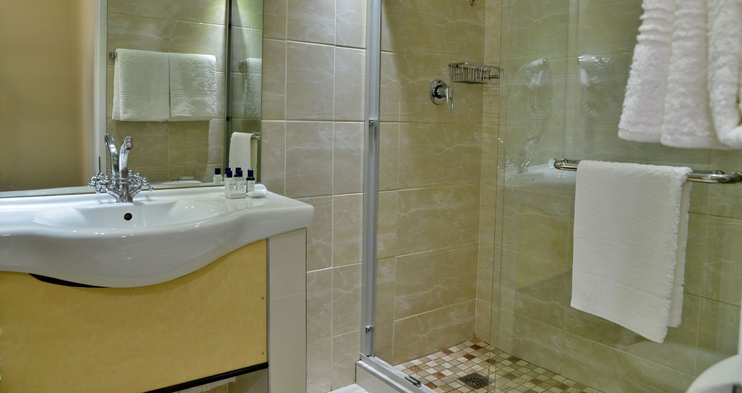 Un baño con lavamanos, espejo y ducha.